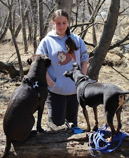 Dog trainer Nickala Squire poses for a photo outside with her two attentive dogs